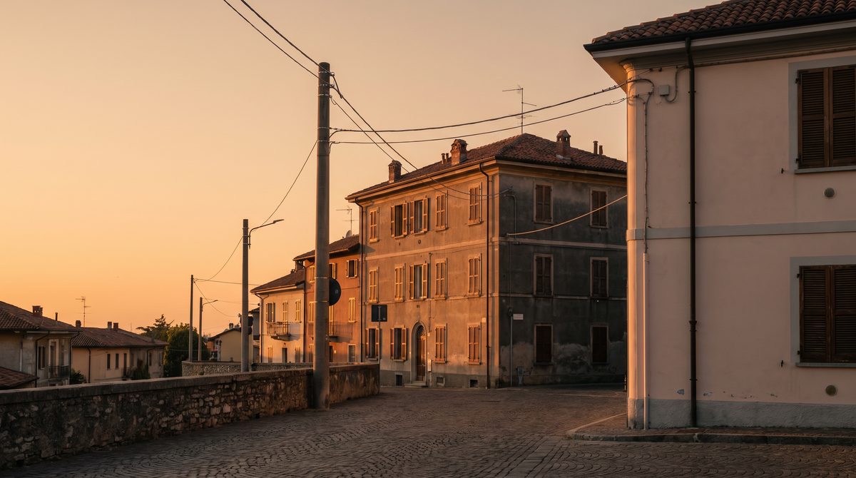 Una strada acciottolata in un borgo italiano illuminata dalla calda luce del tramonto con edifici storici.